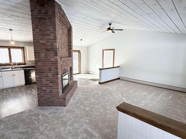 unfurnished living room with lofted ceiling, sink, baseboard heating, a fireplace, and light carpet