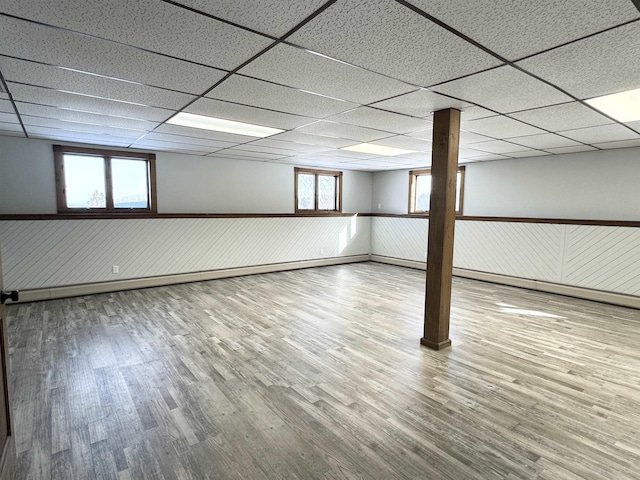 basement featuring wood-type flooring and a paneled ceiling