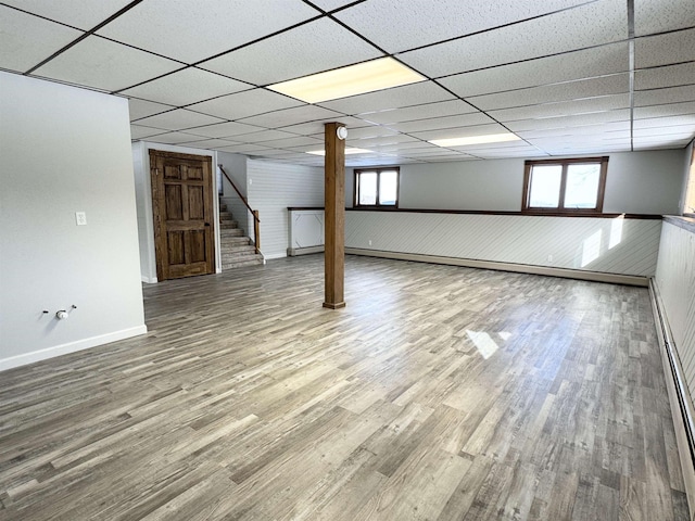 basement featuring a healthy amount of sunlight, hardwood / wood-style floors, and a drop ceiling