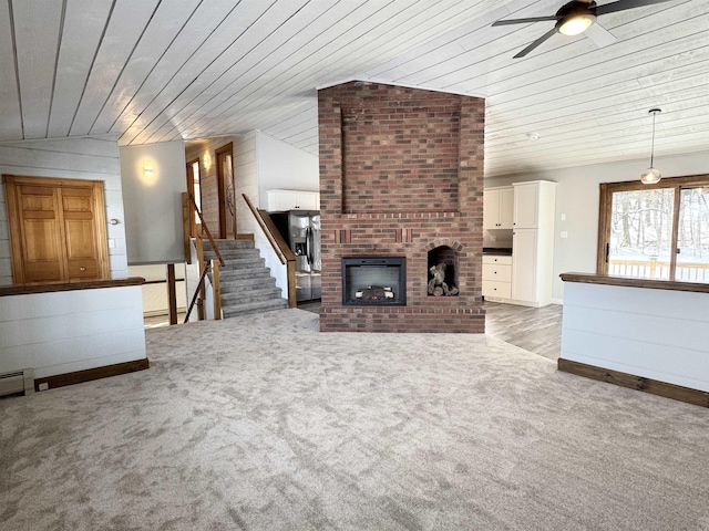 unfurnished living room featuring ceiling fan, light carpet, a brick fireplace, vaulted ceiling, and wooden ceiling