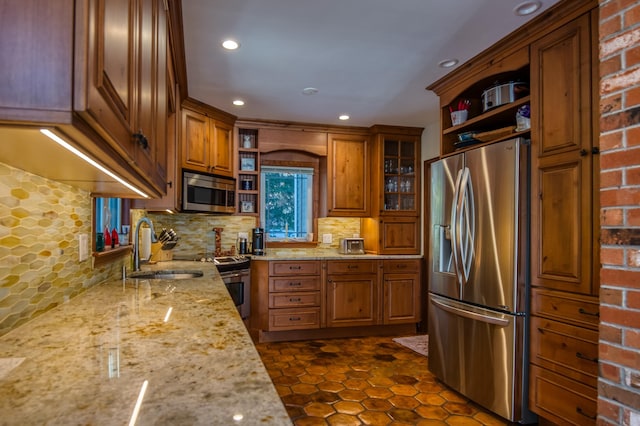 kitchen featuring sink, dark tile patterned floors, appliances with stainless steel finishes, light stone countertops, and decorative backsplash