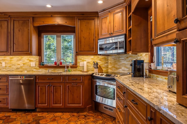 kitchen with light stone counters, stainless steel appliances, sink, and plenty of natural light