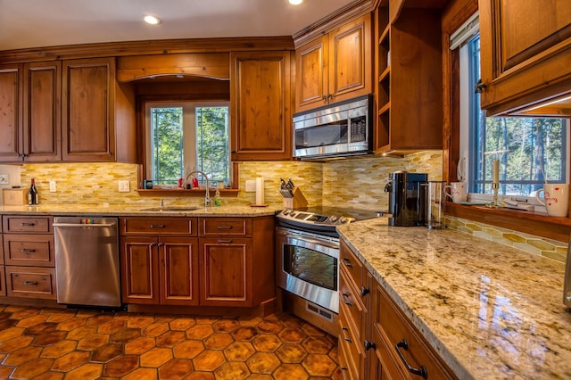 kitchen with light stone counters, appliances with stainless steel finishes, sink, and decorative backsplash