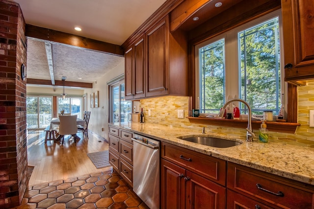 kitchen featuring dishwasher, sink, decorative backsplash, hanging light fixtures, and light stone countertops