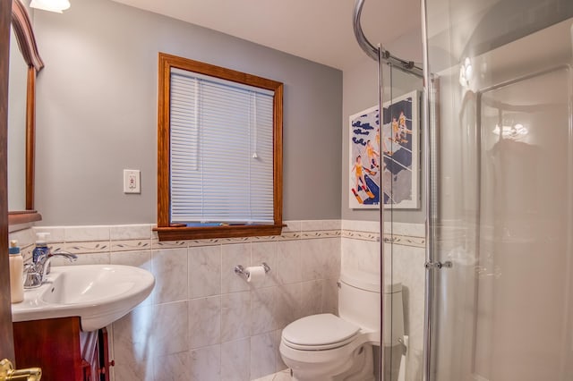 bathroom with tile walls, vanity, a shower with door, and toilet