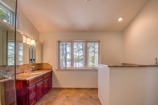 bathroom with vanity, vaulted ceiling, and backsplash