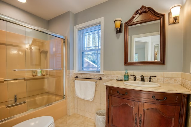 full bathroom featuring tile walls, shower / bath combination with glass door, vanity, toilet, and tile patterned floors