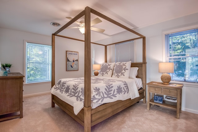 bedroom with multiple windows, light colored carpet, and ceiling fan