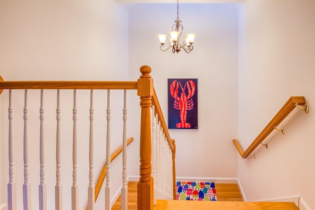 stairs featuring hardwood / wood-style flooring and a notable chandelier