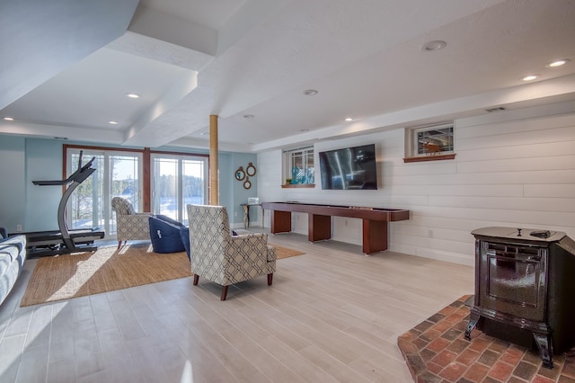 living room with a tray ceiling, light wood-type flooring, and a wood stove