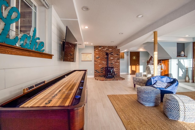 playroom with a wood stove and light wood-type flooring