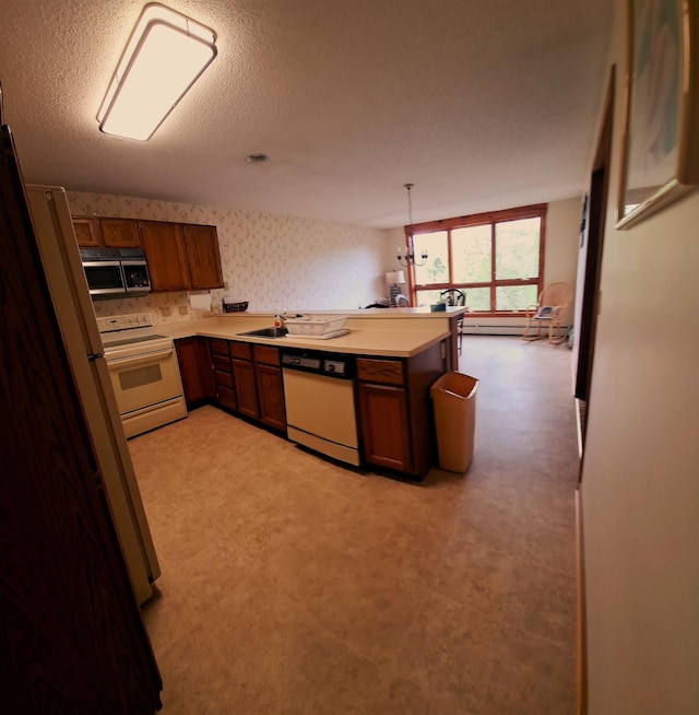 kitchen with pendant lighting, white appliances, and kitchen peninsula