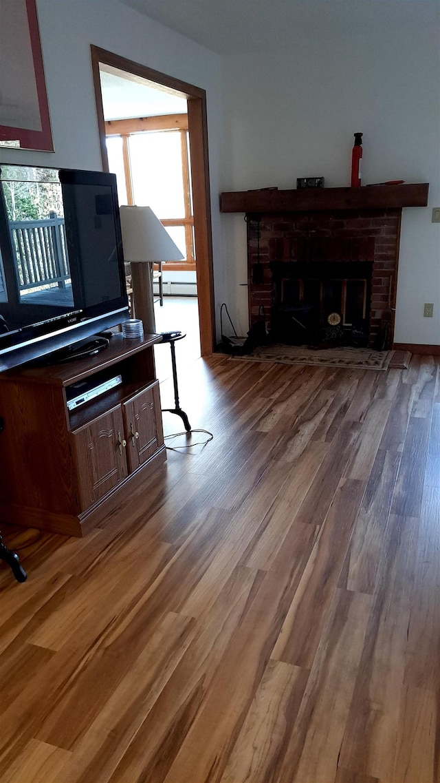 misc room featuring a brick fireplace, hardwood / wood-style floors, and a baseboard heating unit