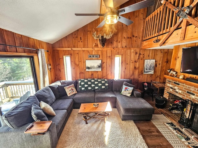 living room featuring wood-type flooring, high vaulted ceiling, ceiling fan, and wood walls