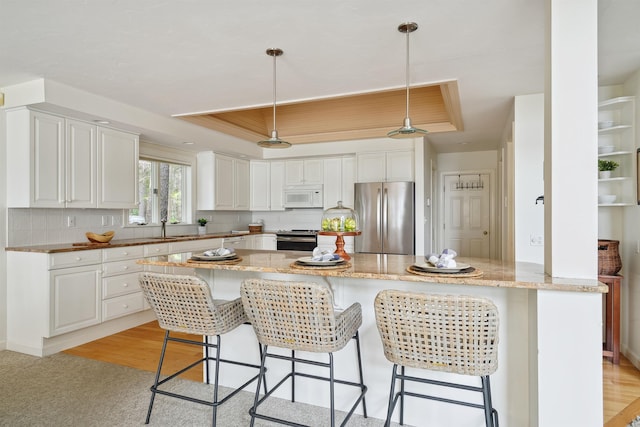 kitchen featuring appliances with stainless steel finishes, white cabinets, and a tray ceiling