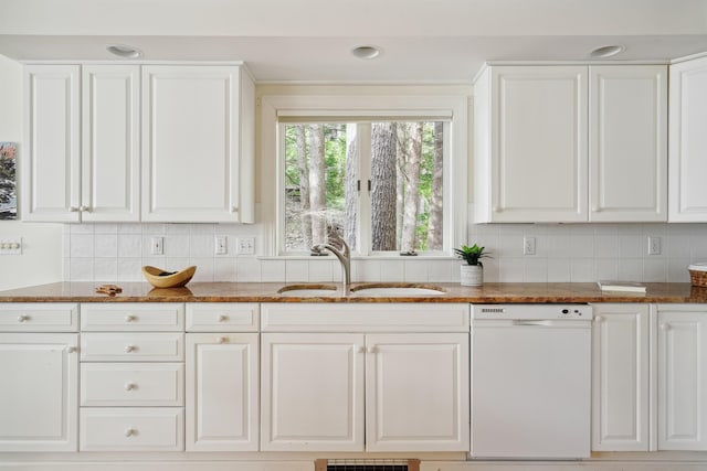 kitchen featuring sink, dishwasher, white cabinetry, backsplash, and dark stone countertops