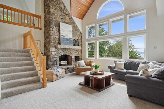 carpeted living room with wood ceiling, a stone fireplace, high vaulted ceiling, and a wealth of natural light