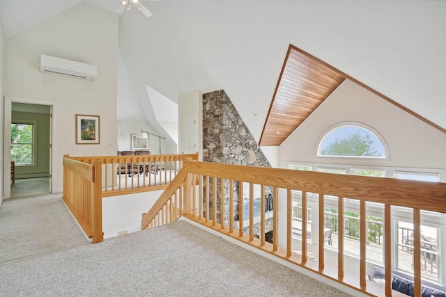 corridor featuring a wall mounted air conditioner, a baseboard radiator, high vaulted ceiling, and carpet flooring