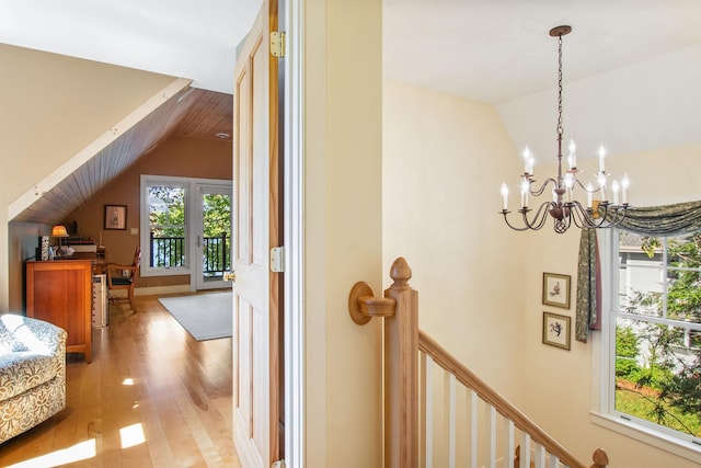 hall featuring vaulted ceiling, a chandelier, and light hardwood / wood-style floors