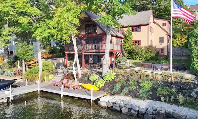 rear view of house with a deck with water view, a balcony, and a patio area