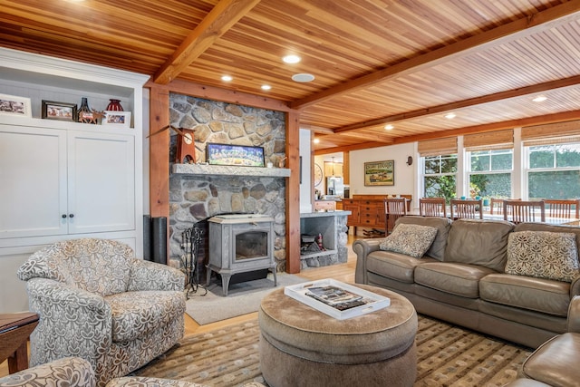 living room featuring beamed ceiling, a wood stove, wood ceiling, and light hardwood / wood-style flooring