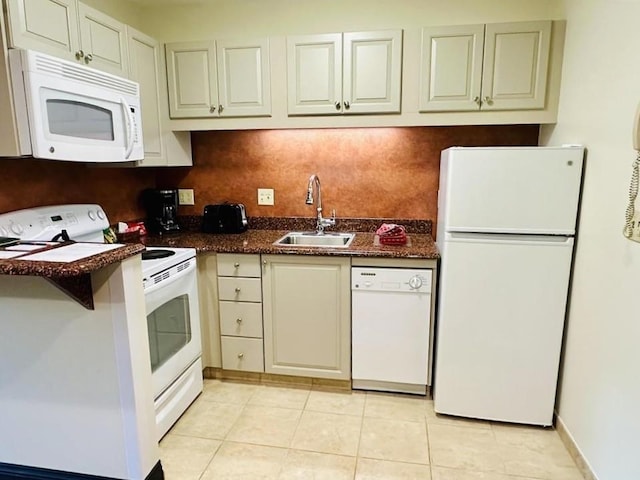 kitchen featuring tasteful backsplash, sink, dark stone counters, light tile patterned floors, and white appliances