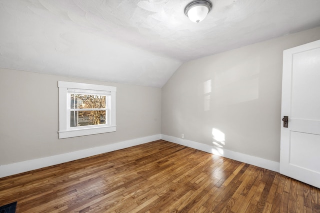 additional living space with vaulted ceiling and wood-type flooring