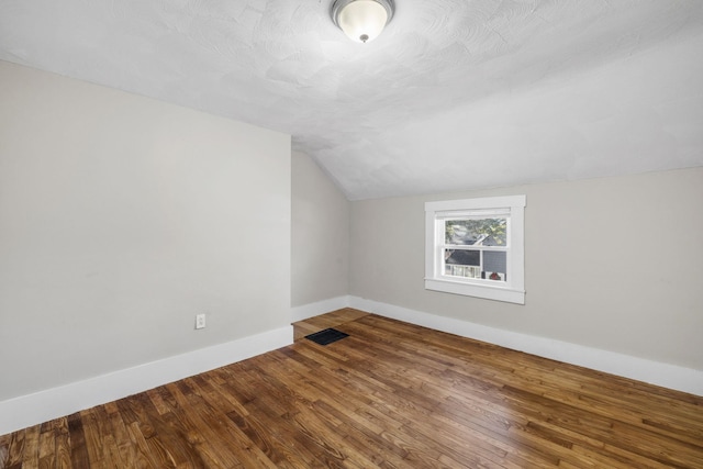 bonus room featuring hardwood / wood-style flooring, vaulted ceiling, and a textured ceiling