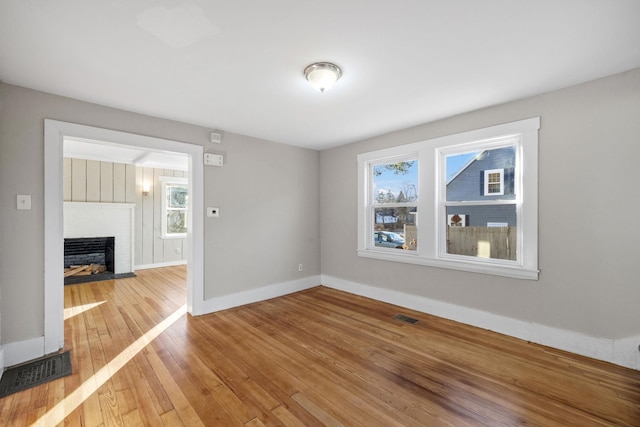 spare room featuring a fireplace, hardwood / wood-style flooring, and a wealth of natural light