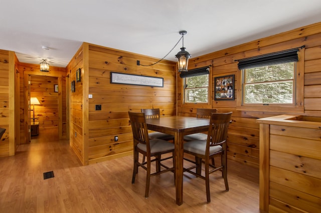 dining room featuring wooden walls and light wood-type flooring