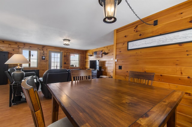 dining room with light hardwood / wood-style floors and wood walls