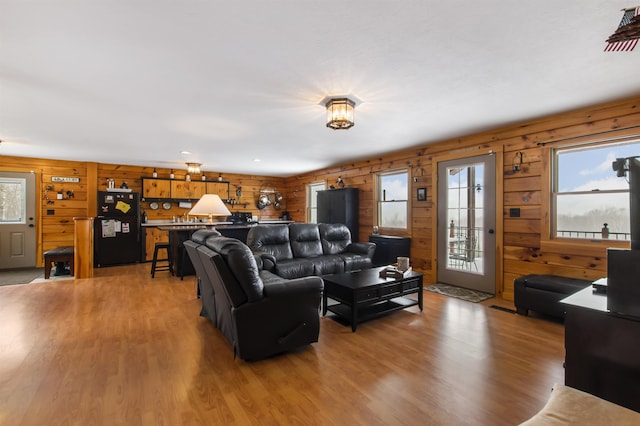 living room with a healthy amount of sunlight, wooden walls, and hardwood / wood-style floors