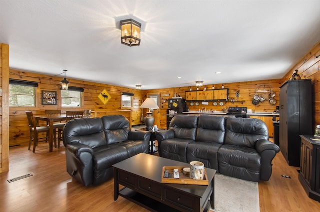 living room with wooden walls and light hardwood / wood-style flooring