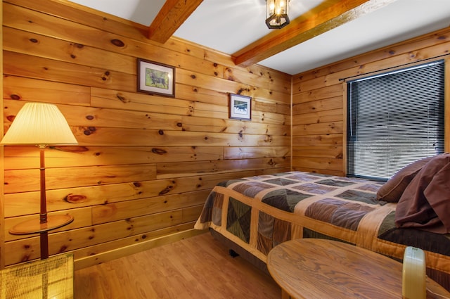 bedroom featuring wooden walls, beam ceiling, and light hardwood / wood-style floors