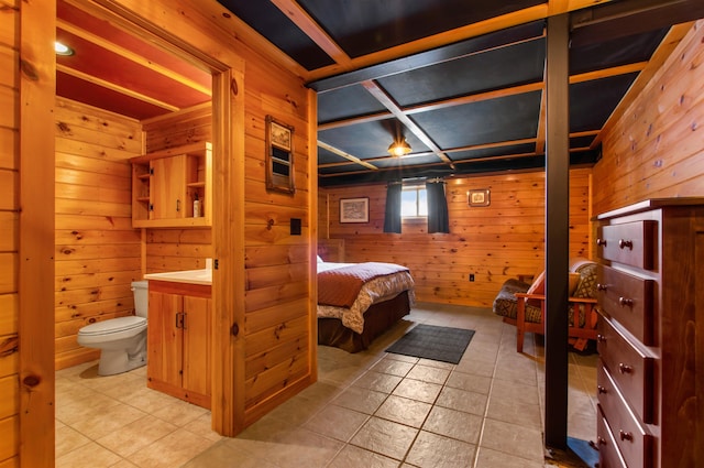 bedroom featuring ensuite bath, tile patterned flooring, and wood walls