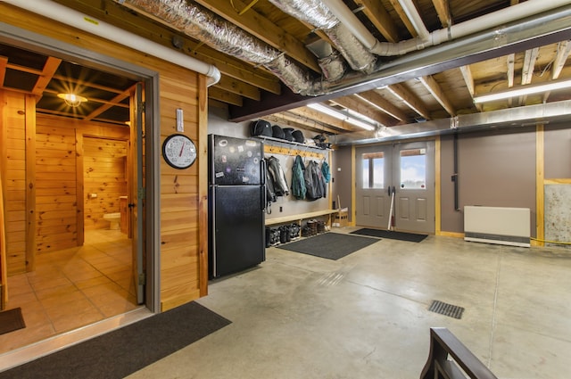 basement featuring black refrigerator and wooden walls