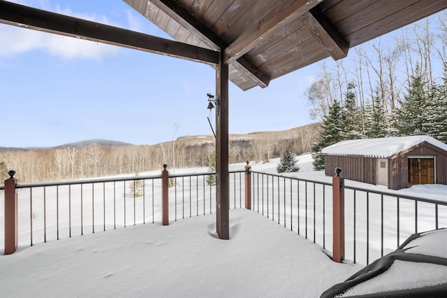 snow covered deck with an outbuilding and a mountain view