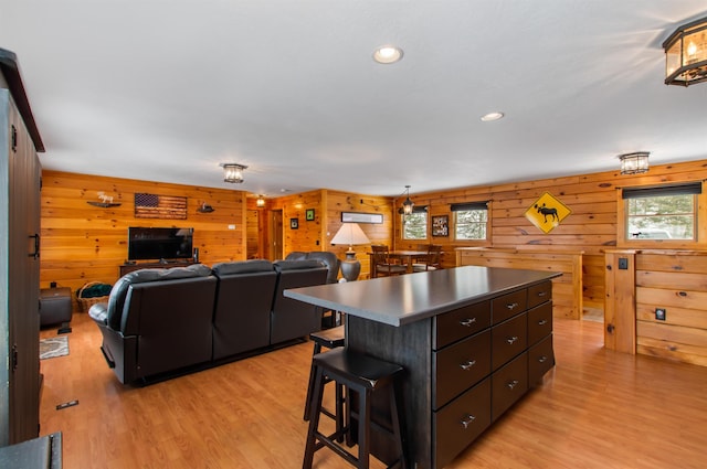 kitchen with dark brown cabinetry, a kitchen island, a breakfast bar, and light hardwood / wood-style floors