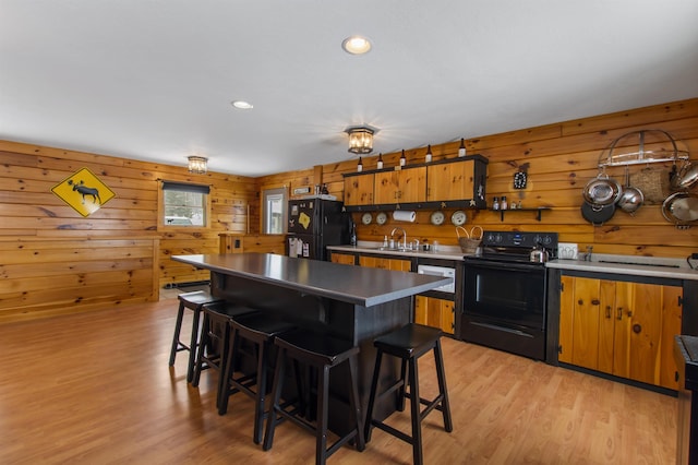 kitchen featuring sink, a kitchen bar, a center island, light hardwood / wood-style floors, and black appliances