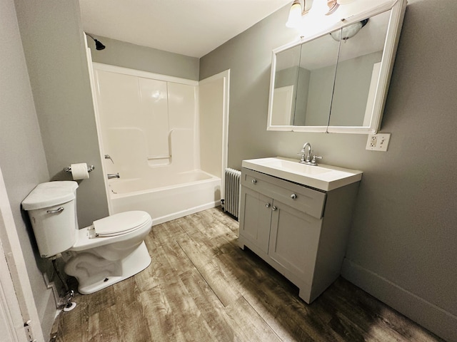 full bathroom featuring radiator, hardwood / wood-style flooring, vanity, toilet, and tub / shower combination