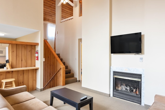 living room with a high ceiling, light carpet, a fireplace, and ceiling fan