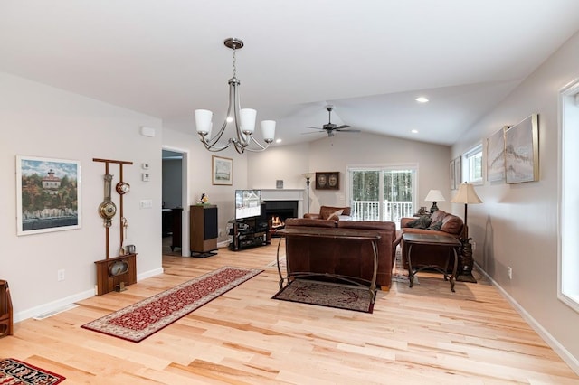 living room with light hardwood / wood-style flooring, ceiling fan with notable chandelier, and vaulted ceiling