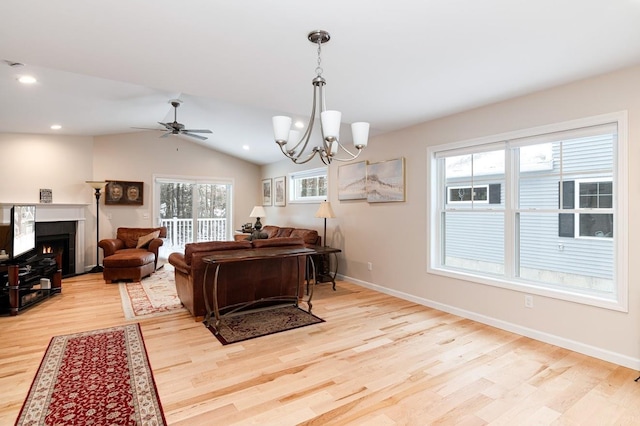 living room featuring lofted ceiling, ceiling fan with notable chandelier, and light wood-type flooring