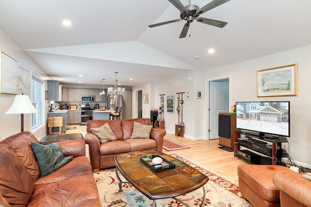 living room with ceiling fan with notable chandelier, vaulted ceiling, and light wood-type flooring