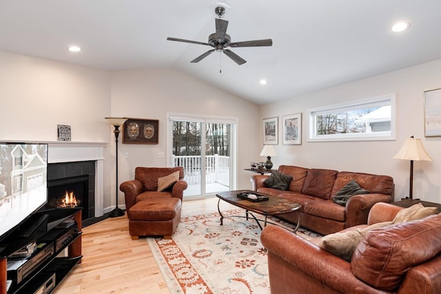 living room featuring lofted ceiling, a fireplace, plenty of natural light, and light wood-type flooring