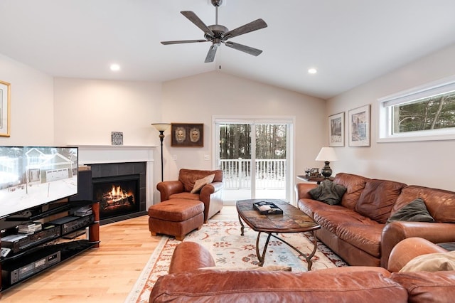 living room with lofted ceiling, hardwood / wood-style floors, a tiled fireplace, and a wealth of natural light