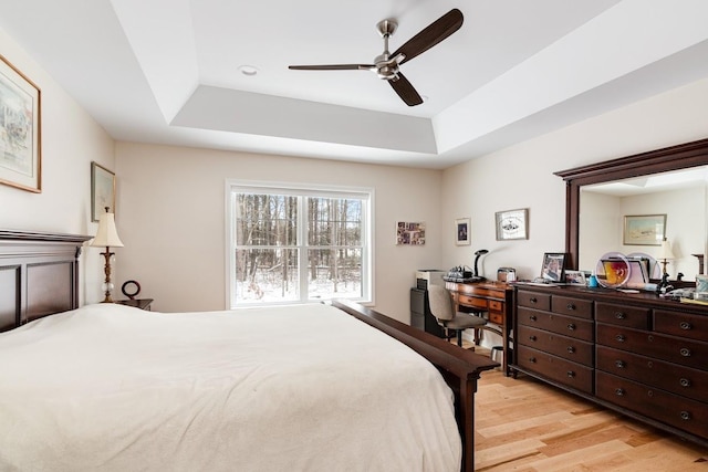 bedroom featuring light hardwood / wood-style floors, a raised ceiling, and ceiling fan