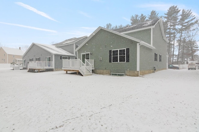 snow covered rear of property with a wooden deck