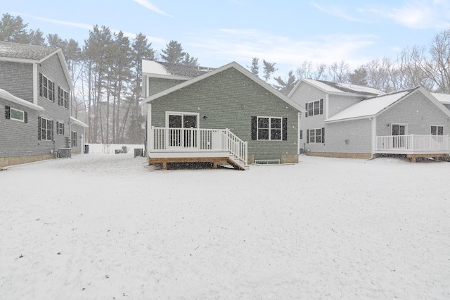 snow covered house with central AC and a deck