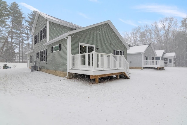 snow covered house with a wooden deck